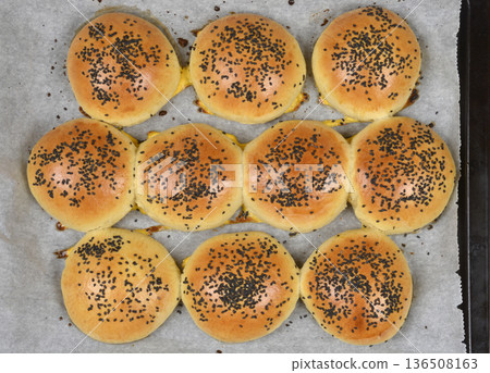 Baked burger buns with black sesame seeds on a baking sheet Baked burger buns with black sesame seeds on a baking sheet 136508163