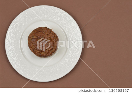 Small banana bread loaf on a white plate over a brown background 136508167