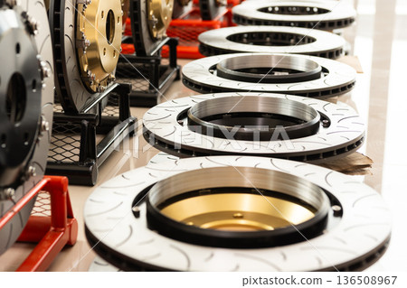 Close up brake disc rotors with drilled and slotted surface performance automotive parts displayed in workshop high quality metal components for vehicle braking system Close up brake disc rotors with drilled and slotted surface performance automotive parts displayed in workshop high quality metal components for vehicle braking system 136508967