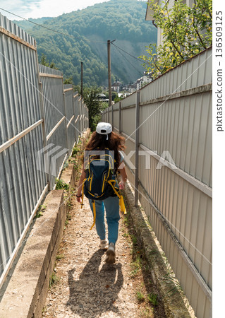 Female Traveler with Backpack Walking Through Mountain Village Female Traveler with Backpack Walking Through Mountain Village 136509125