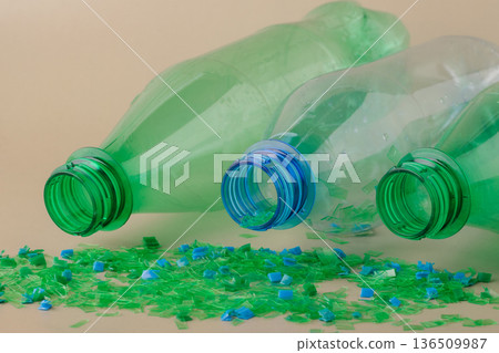 Empty plastic bottles spilling colorful crushed microplastic flakes illustrate the process of recycling and material recovery. Circular economy, green technologies Empty plastic bottles spilling colorful crushed microplastic flakes illustrate the process of recycling and material recovery. Circular economy, green technologies 136509987