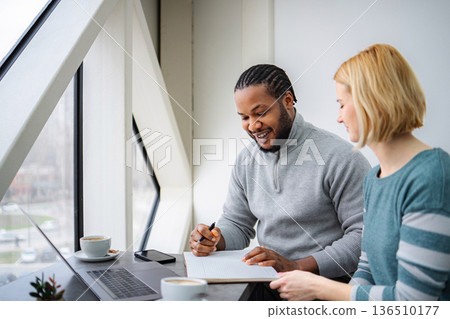 Two diverse adults working together in a cafe, planning strategy Two diverse adults working together in a cafe, planning strategy 136510177