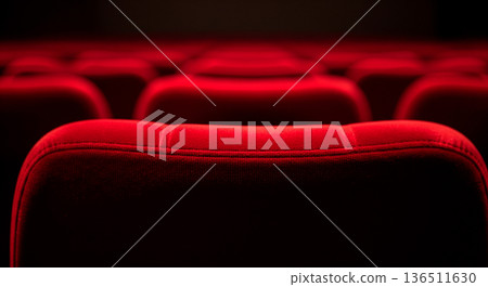 Rows of empty plush red velvet theater seats in dim lighting, ready for an audience Rows of empty plush red velvet theater seats in dim lighting, ready for an audience 136511630