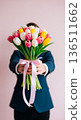 Man in a suit holding a colorful bouquet of tulips tied with a pink ribbon 136511662