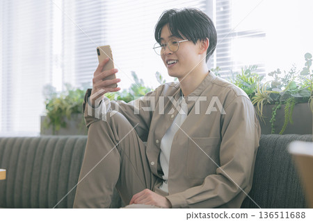 一個男人看著房間裡的智能手機 136511688