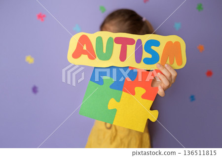School concept of autism awareness with child holding colorful puzzle pieces and autism sign. Inclusive education, classroom support, neurodiversity acceptance and equal learning opportunities. School concept of autism awareness with child holding colorful puzzle pieces and autism sign. Inclusive education, classroom support, neurodiversity acceptance and equal learning opportunities. 136511815