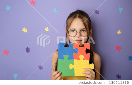 Portrait of schoolgirl holding colorful puzzle pieces symbolizing autism awareness. Inclusive education, school support, equal learning opportunities and classroom inclusion concept. Portrait of schoolgirl holding colorful puzzle pieces symbolizing autism awareness. Inclusive education, school support, equal learning opportunities and classroom inclusion concept. 136511816
