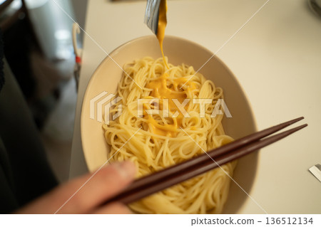 男人在廚房吃拌有義大利麵醬的麵條。 男人在廚房吃拌有義大利麵醬的麵條。 136512134