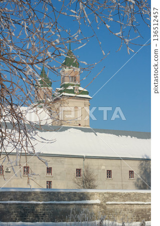 Old monastery towers with green roofs in a sunny winter day with hoarfrost branches Old monastery towers with green roofs in a sunny winter day with hoarfrost branches 136512457