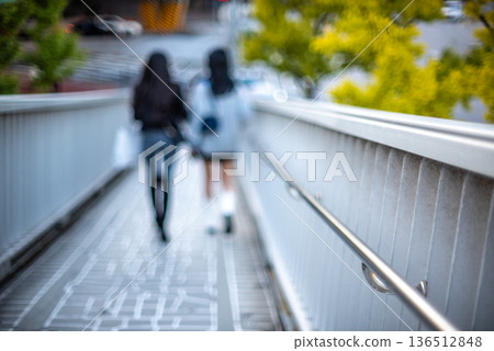 Two girls walking on a blurred urban bridge Two girls walking on a blurred urban bridge 136512848