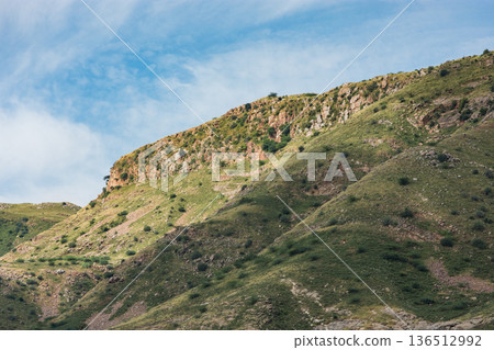 Rocky cliff on grassy hillside under blue sky in rural Rajasthan, India Rocky cliff on grassy hillside under blue sky in rural Rajasthan, India 136512992