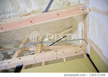 Image of a house: Spray insulation on a wooden single-story house under construction Image of a house: Spray insulation on a wooden single-story house under construction 136513206