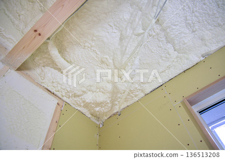 Image of a house: Spray insulation on a wooden single-story house under construction Image of a house: Spray insulation on a wooden single-story house under construction 136513208