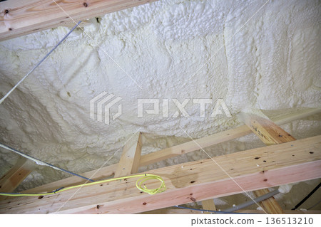 Image of a house: Spray insulation on a wooden single-story house under construction Image of a house: Spray insulation on a wooden single-story house under construction 136513210