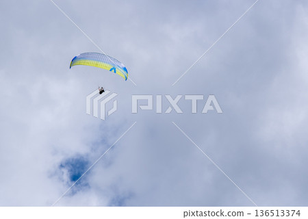 Paraglider soaring in cloudy sky with copy space 136513374