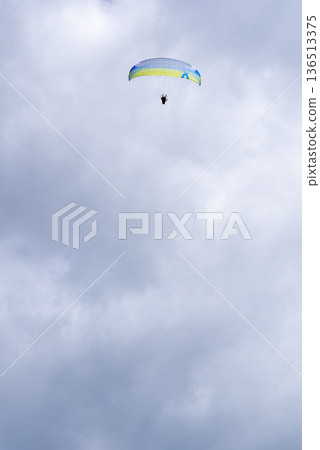 Paraglider soaring in cloudy sky with copy space 136513375