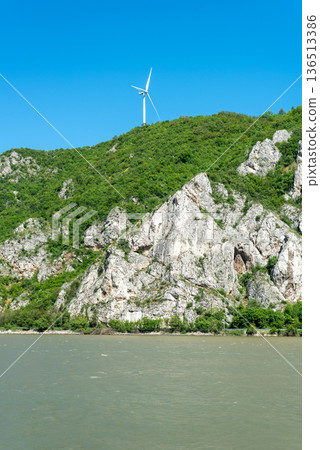 Wind turbine on forested mountain above rocky river cliffs Wind turbine on forested mountain above rocky river cliffs 136513386