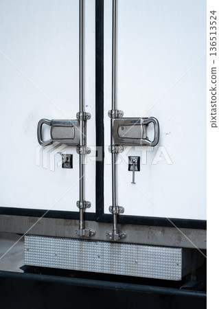 Truck trailer featuring closed white rear doors with metallic hinges and latches, emphasizing secure logistics and transportation while delivering cargo Truck trailer featuring closed white rear doors with metallic hinges and latches, emphasizing secure logistics and transportation while delivering cargo 136513524