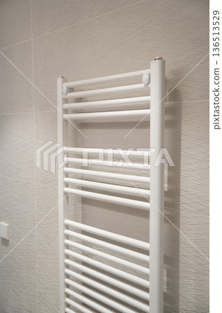 White wall-mounted heated towel rail providing warmth and drying towels, integrating modern home amenities with minimalist bathroom decor and comfort concepts White wall-mounted heated towel rail providing warmth and drying towels, integrating modern home amenities with minimalist bathroom decor and comfort concepts 136513529