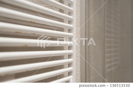 White towel radiator showing rust and corrosion, indicating maintenance problems and plumbing issues in a domestic bathroom, needing repair 136513530