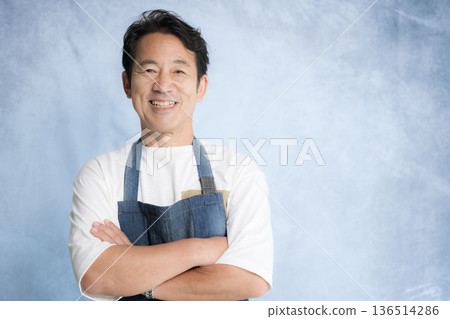 Senior man wearing an apron, image of a craftsman or craftsman, looking at the camera with a smile Senior man wearing an apron, image of a craftsman or craftsman, looking at the camera with a smile 136514286