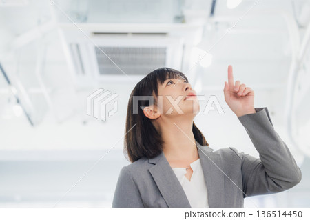 一位面露不滿的女商人看著冷氣。 136514450