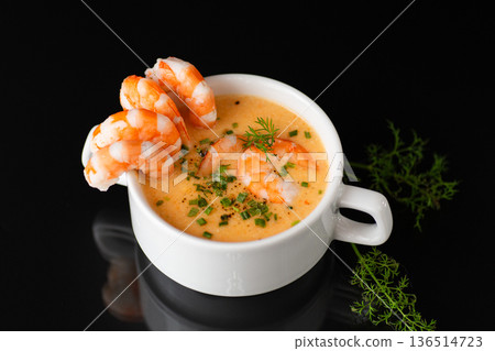 Delicious creamy shrimp bisque presented on glossy black reflective surface 136514723