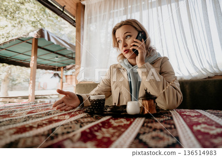 Woman Talking on Phone at a Cafe Woman Talking on Phone at a Cafe 136514983