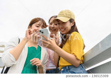 Friends looking at their smartphones ■ Photo courtesy of Kansai International Airport (KIX) Friends looking at their smartphones ■ Photo courtesy of Kansai International Airport (KIX) 136515309