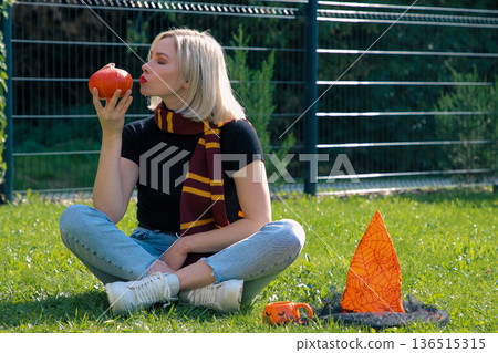 A beautiful girl is sitting on the terrace with a dog, holding a pumpkin in her hand. A beautiful girl is sitting on the terrace with a dog, holding a pumpkin in her hand. 136515315