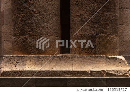 Warm-lit ancient stone columns and a massive base 136515717