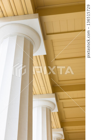 Sunlit columned arcade with tall white pillars Sunlit columned arcade with tall white pillars 136515729