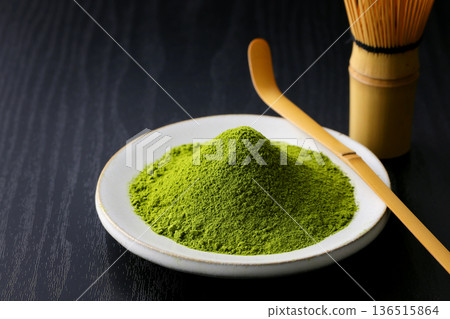 Vibrant green matcha powder stands out against a black wood grain background 136515864