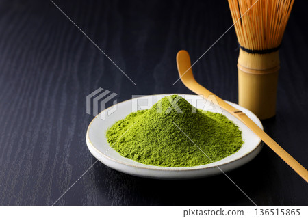 Vibrant green matcha powder stands out against a black wood grain background 136515865