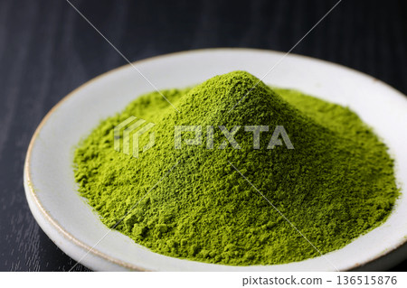 Vibrant green matcha powder stands out against a black wood grain background 136515876