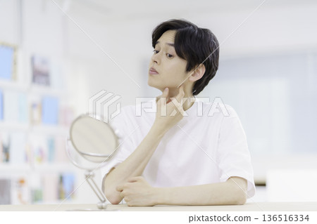 Men's Beauty: A young Japanese man looking in the mirror and worrying about the shave on his chin 136516334