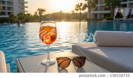 Vibrant Orange Spritz Cocktail on Poolside Table Under Clear Sky Vibrant Orange Spritz Cocktail on Poolside Table Under Clear Sky 136516735