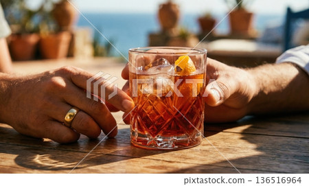 Refreshing Negroni Cocktail Held Over Mediterranean Sea View 136516964