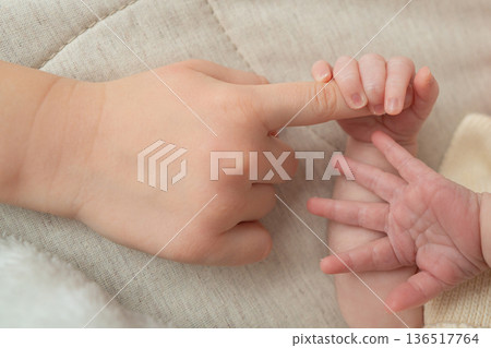 Close-up shot of a newborn baby hand gently holding the finger of an older child. The image focuses on connection, care, and family bond, symbolizing protection, love, and tenderness between siblings Close-up shot of a newborn baby hand gently holding the finger of an older child. The image focuses on connection, care, and family bond, symbolizing protection, love, and tenderness between siblings 136517764