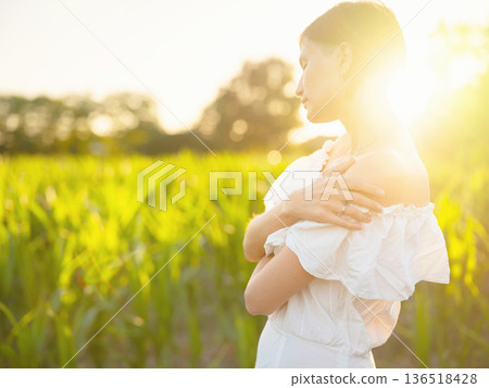 Woman in white dress walking through sunset field in Croatia Woman in white dress walking through sunset field in Croatia 136518428