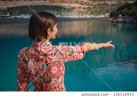 Woman in red Outfit Looking Out Over Cliff Into Water 136518433