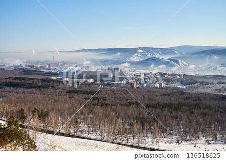 Panoramic view of Krasnoyarsk city in winter. Urban landscape with snowy mountains, forest, and buildings, showing development concept. Panoramic view of Krasnoyarsk city in winter. Urban landscape with snowy mountains, forest, and buildings, showing development concept. 136518625
