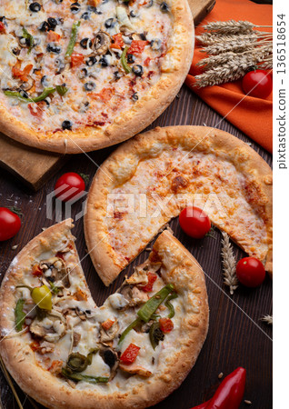 assortiment of tasty fresh Pizza. served at wooden table with cherry tomatos and wheat ears. flat lay. assortiment of tasty fresh Pizza. served at wooden table with cherry tomatos and wheat ears. flat lay. 136518654