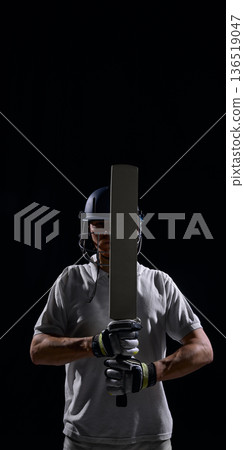 Cricket player gripping bat in centered dramatic studio portrait. Cricket player gripping bat in centered dramatic studio portrait. 136519047