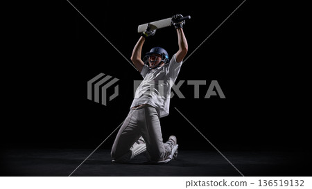 Cricket player kneeling on dark background celebrating decisive win. Cricket player kneeling on dark background celebrating decisive win. 136519132