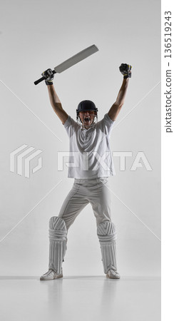 Cricket player celebrating victory with raised bat isolated on white background. Cricket player celebrating victory with raised bat isolated on white background. 136519243