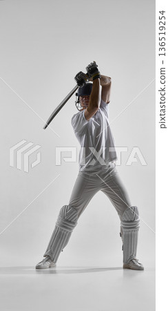 Cricket player holding bat ready to strike isolated on white background Cricket player holding bat ready to strike isolated on white background 136519254