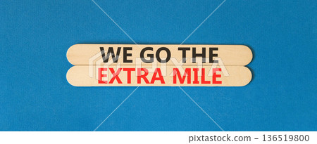Support, help we go the extra mile symbol. Concept words We go the extra mile on beautiful wooden sticks. Beautiful blue background. Business we go the extra mile concept. Copy space. 136519800