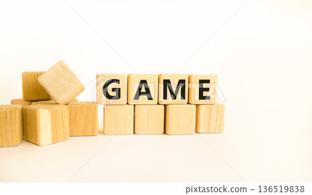 Game symbol. Concept word Game on beautiful wooden blocks. Beautiful white table white background. Business, lifestyle and game concept. Copy space. Game symbol. Concept word Game on beautiful wooden blocks. Beautiful white table white background. Business, lifestyle and game concept. Copy space. 136519838