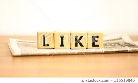 Like symbol. Concept word Like on beautiful wooden blocks on newspaper. Beautiful wooden table white background. Business, lifestyle, support and like concept. Copy space. 136519840